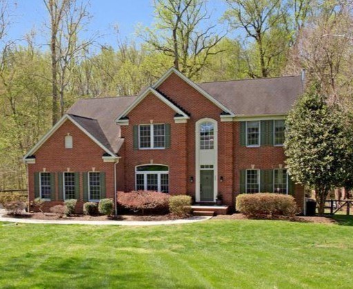 Brick home with a broad lawn and wooded Davidsonville setting
